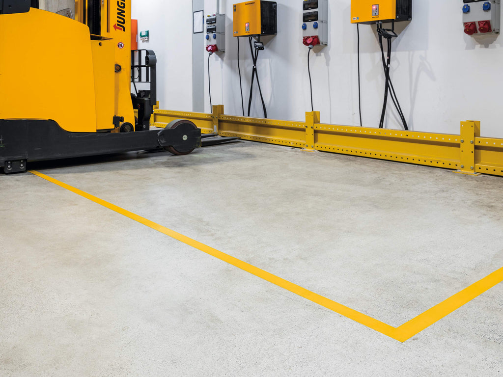 Yellow DURALINE STRONG lines marking out a bay beside a parked pallet stacker and wall chargers