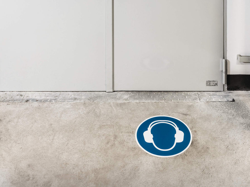 Durable ear protection floor sign in front of a white door