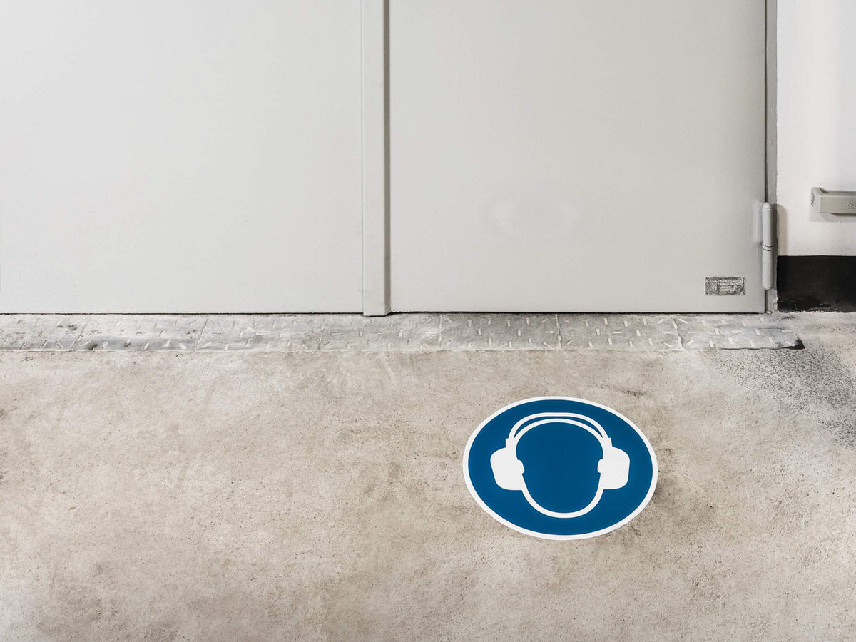 Durable ear protection floor sign in front of a white door
