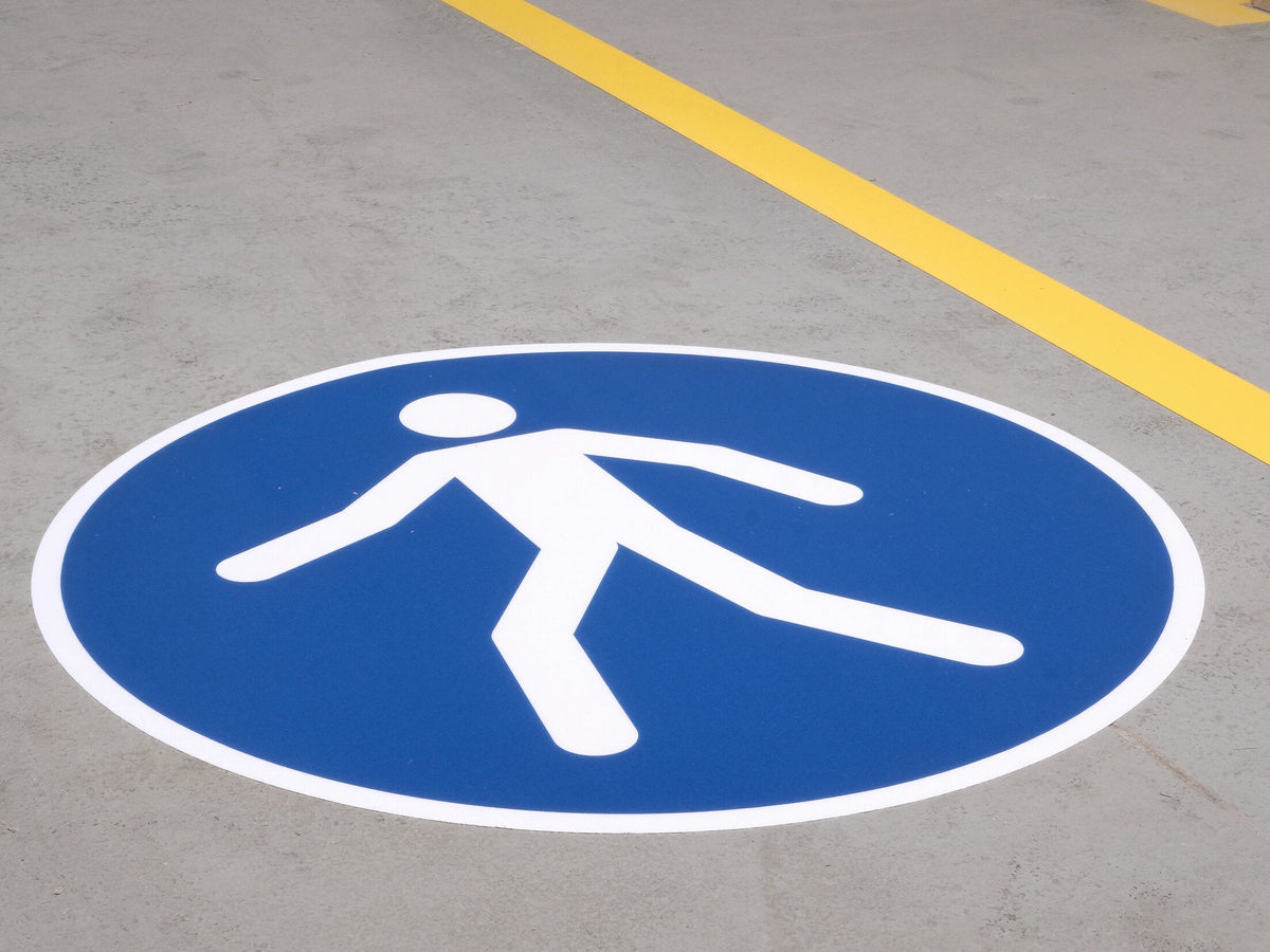 Durable use walkway sign laid on a grey floor beside a yellow line