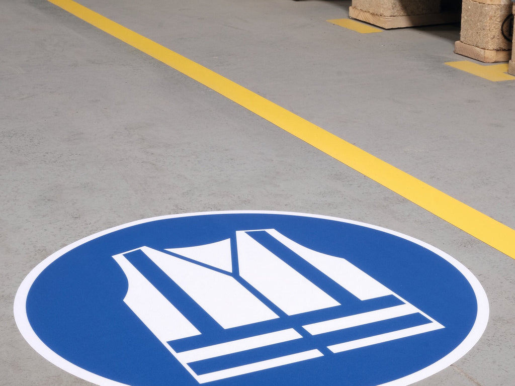 Durable safety vest floor sign laid on a grey floor beside a yellow line