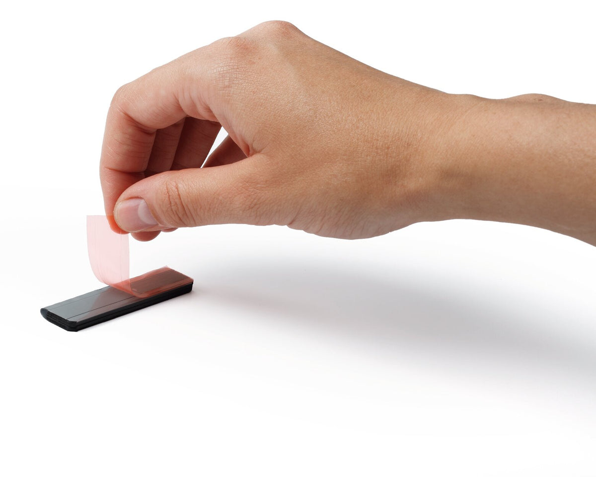 Hand peeling the backing liner off the self-adhesive back of a Durable Durafix clip