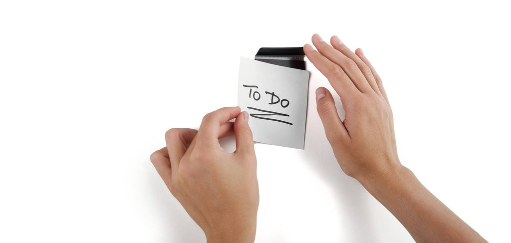 Hands sliding a To Do note under a Durable Durafix clip on a white surface