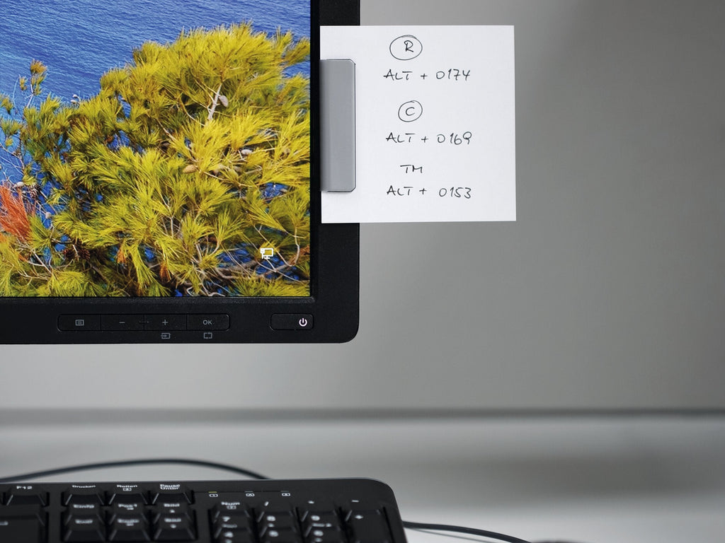 Durable Durafix clip in silver fixed beside a monitor screen with a note of keyboard shortcuts