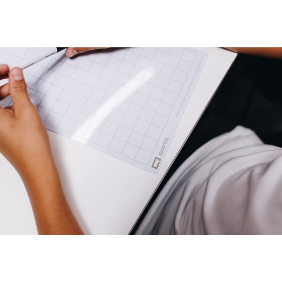 Student hands resting on the grid side of a Quartet Flex A4 board at a desk