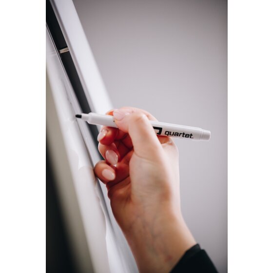 Hand writing with a Quartet Flex whiteboard marker near the edge of a whiteboard