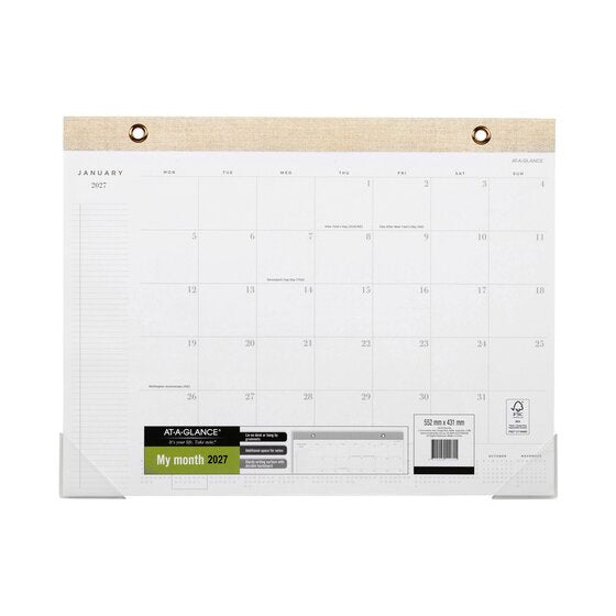 At-A-Glance AAG100127 2027 monthly desk pad open at January with a linen look headband and two grommets, clear corner protectors and the My month 2027 sleeve reading Lie on desk or hang by grommets.