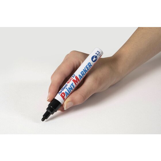 Hand writing with a black Artline 400XF paint marker on a pale grey surface