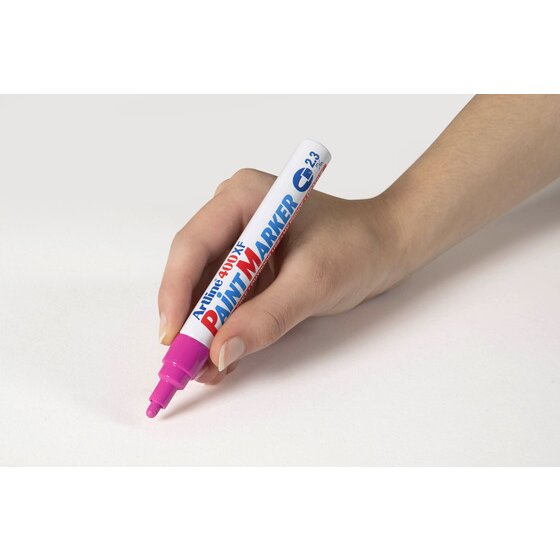 Hand writing with a pink Artline 400XF paint marker on a pale grey surface