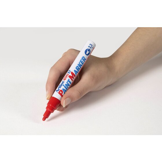 Hand writing with a red Artline 400XF paint marker on a pale grey surface