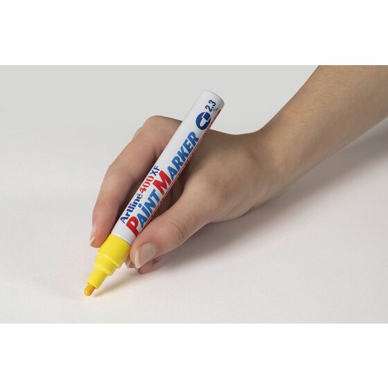 Hand writing with a yellow Artline 400XF paint marker on a pale grey surface