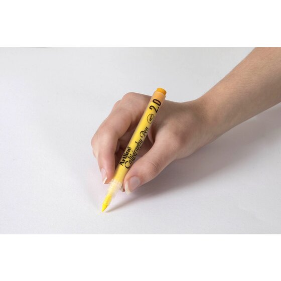 Hand writing with a pastel yellow Artline Calligraphy Pen 2.0